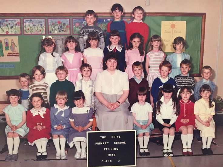 a group of children and adults posing for a photo in front of a chalkboard