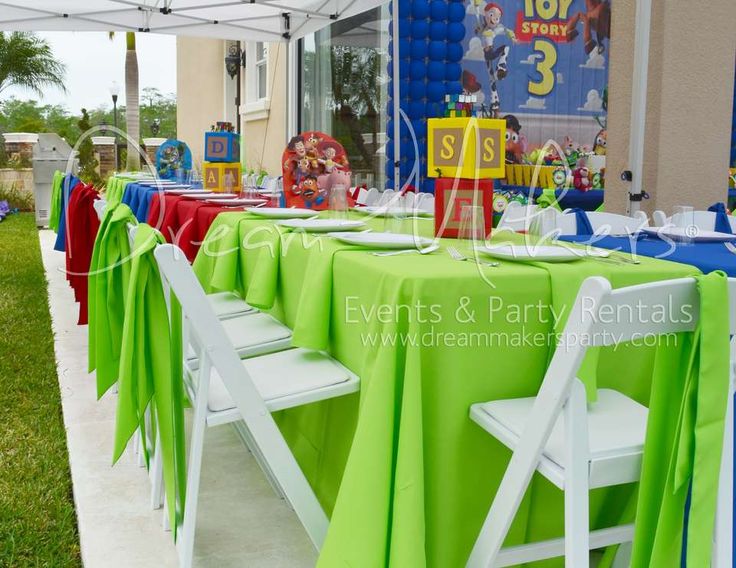 there is a table set up with green and blue cloths for an outdoor party