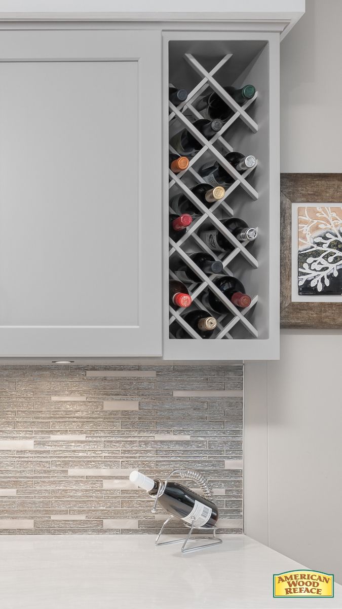 a wine rack in the middle of a kitchen counter with white cabinets and marble backsplash