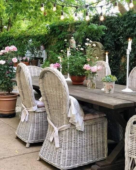 wicker chairs around a table with candles and flowers