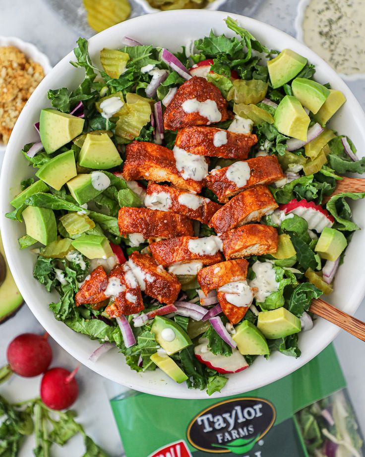 a salad in a bowl with dressing on the side next to other foods and condiments