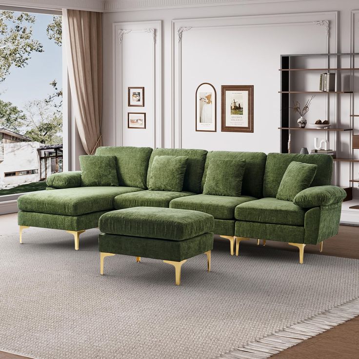 a living room with a large green sectional couch and matching footstool in front of a window