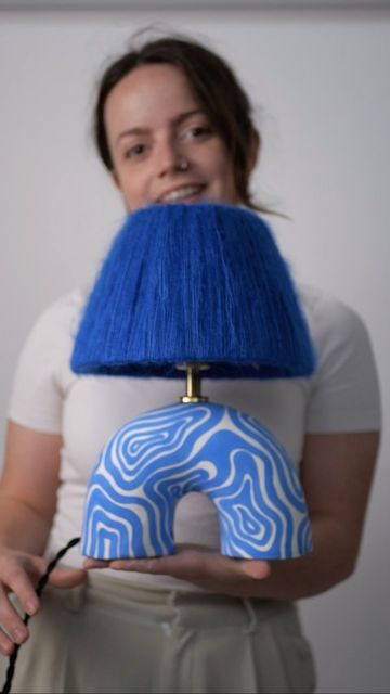 a woman holding a blue and white donut shaped lamp