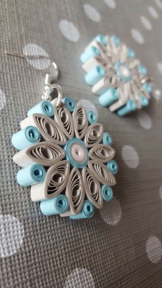 two pieces of jewelry sitting on top of a polka dot tablecloth with white and blue beads