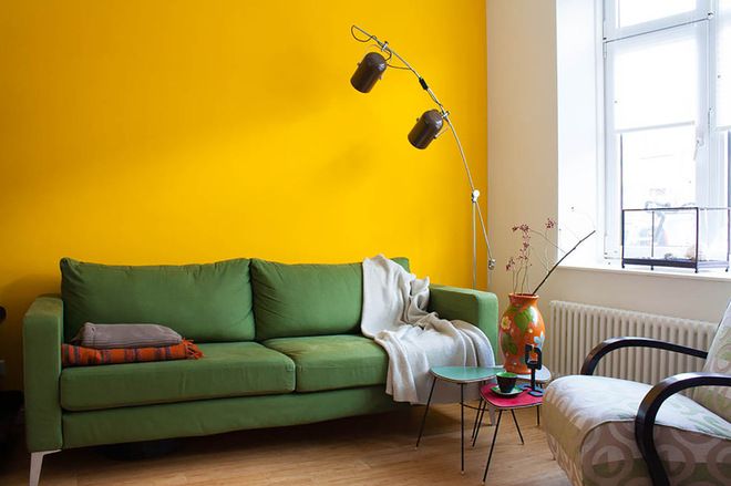 a living room with yellow walls and green couches in front of the window,