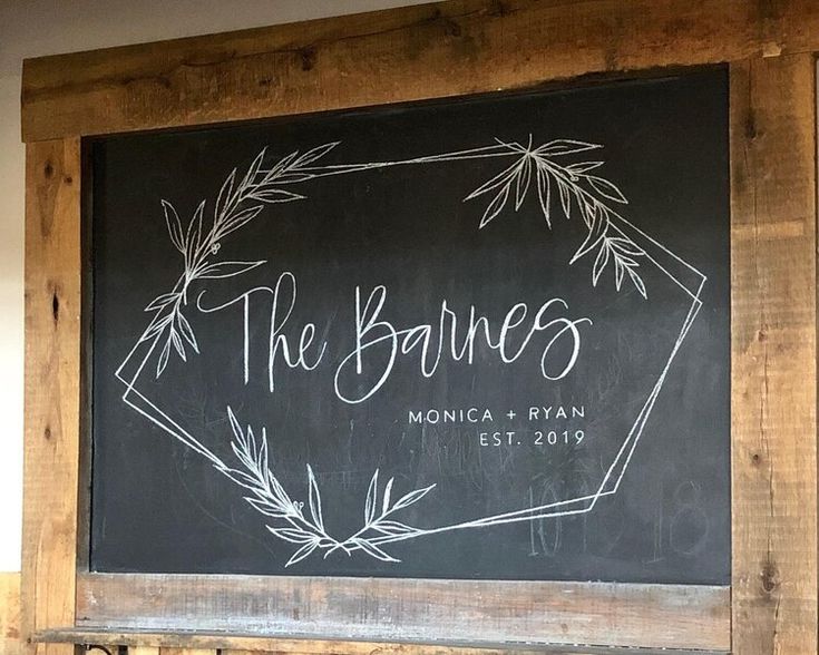 a chalkboard with the names of two couples on it in front of a wooden frame