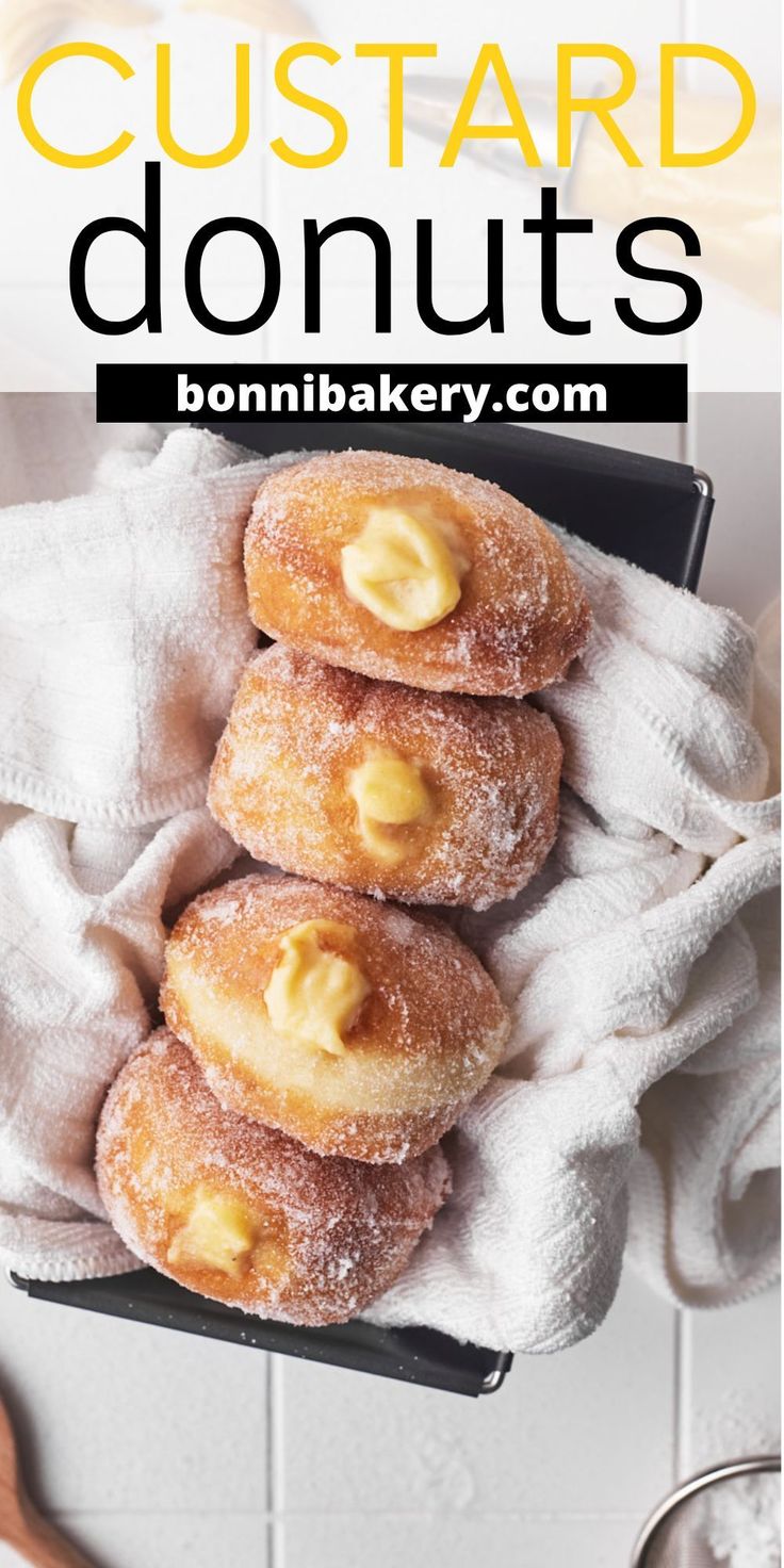 some sugared donuts are in a black box on a white towel with the words custard donuts above them