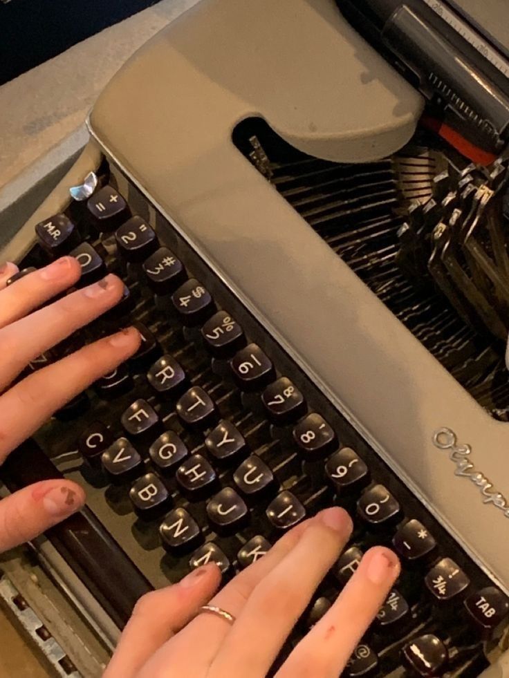 two hands typing on an old fashioned typewriter