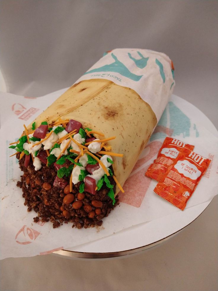 a burrito with beans, cheese and lettuce on it sitting on top of a paper plate