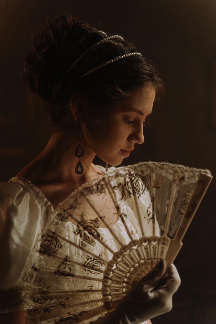 a woman in a white dress holding an old fashioned hand fan with writing on it