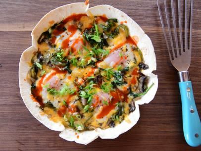 a dish with vegetables and sauce in it next to a spatula on a wooden table