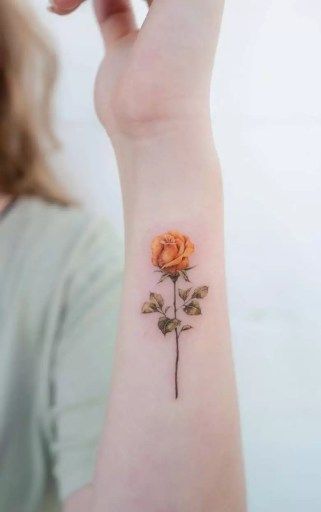 a woman's arm with a small rose tattoo on the left side of her wrist