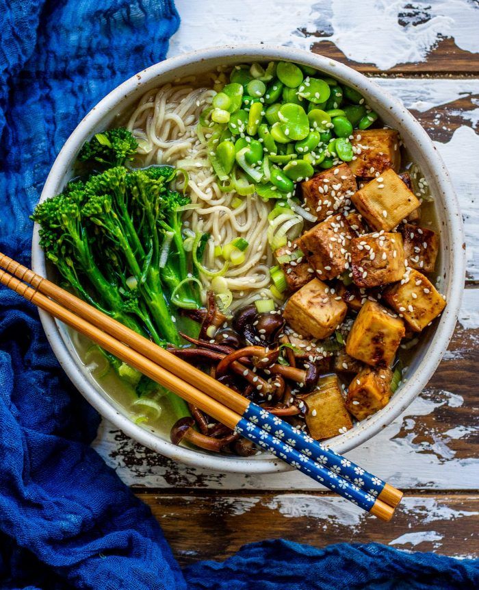 a bowl filled with noodles, broccoli and tofu