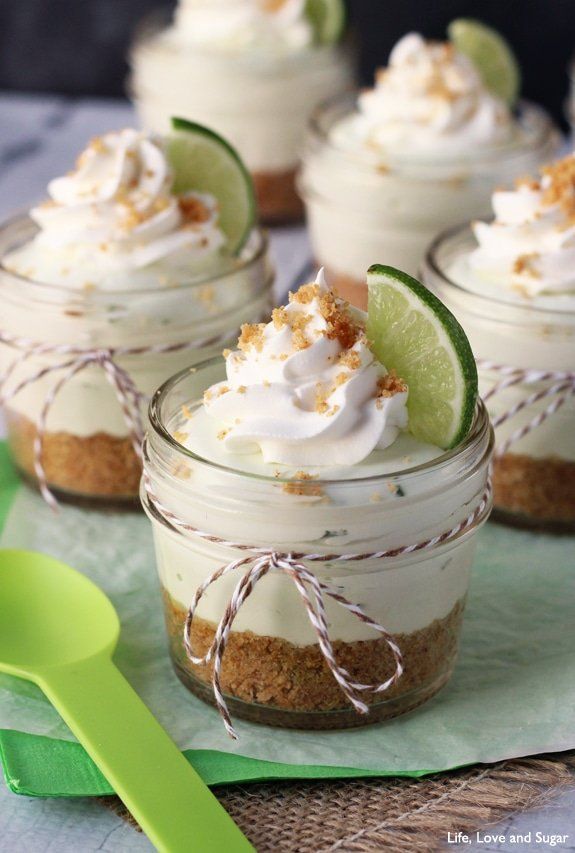 small desserts with lime and whipped cream in glass jars on green napkin next to utensils