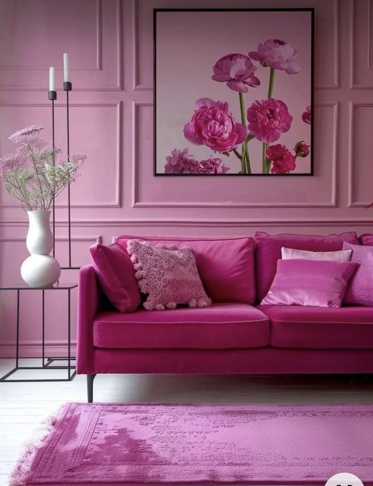 a living room with pink furniture and flowers in vases on the wall behind it