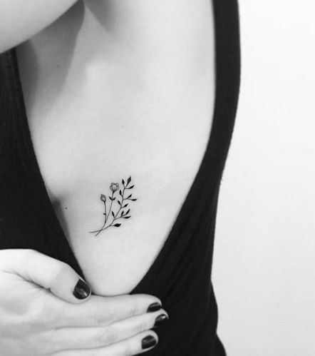 black and white photo of woman's chest with small flower tattoo on her left side