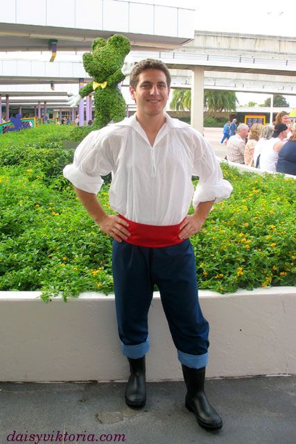 a man dressed in pirate clothing standing next to a hedge