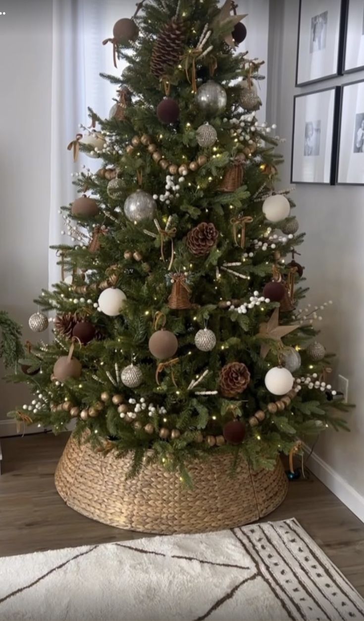 a small christmas tree with ornaments in a basket on the floor next to a window