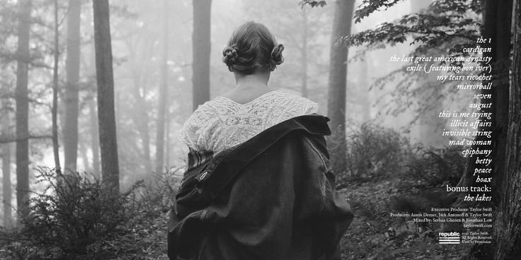 a woman is walking through the woods with her back to the camera