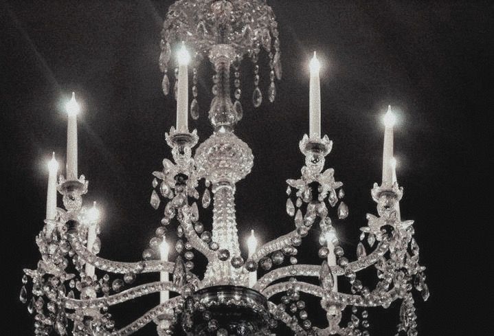 a crystal chandelier with candles lit up in the dark night, black and white photograph