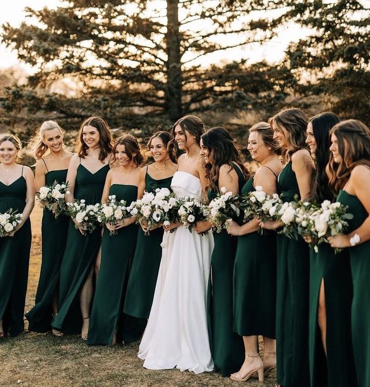 a group of women standing next to each other holding bouquets in their hands and wearing green dresses