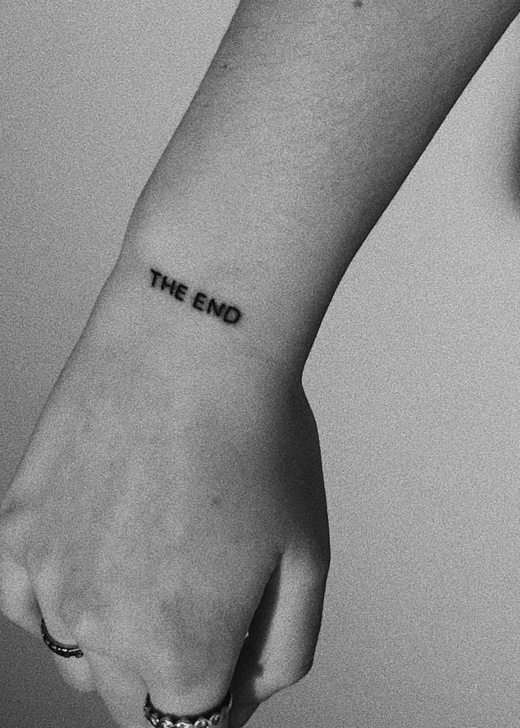 a woman's wrist tattoo with the word the end written on her left arm