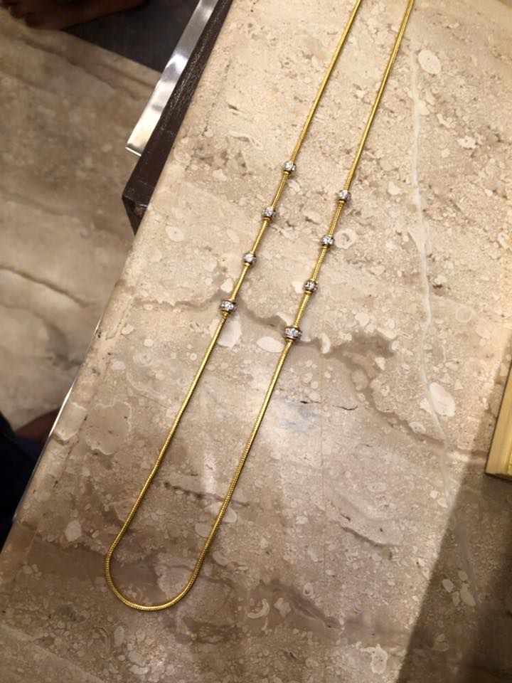 two long necklaces sitting on top of a marble counter next to a metal object