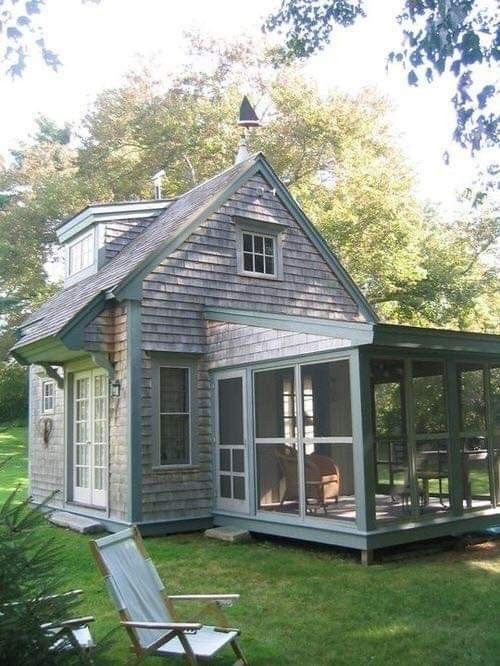 a small gray house sitting on top of a lush green field