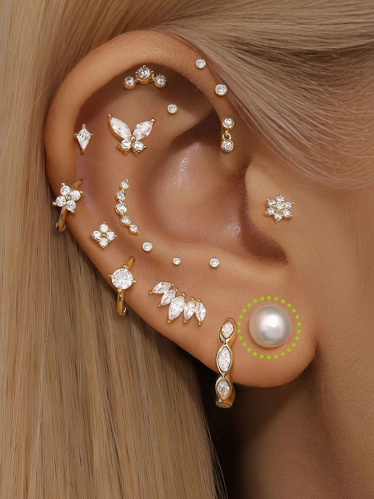 a close up of a woman's ear with butterfly and pearl studs on it