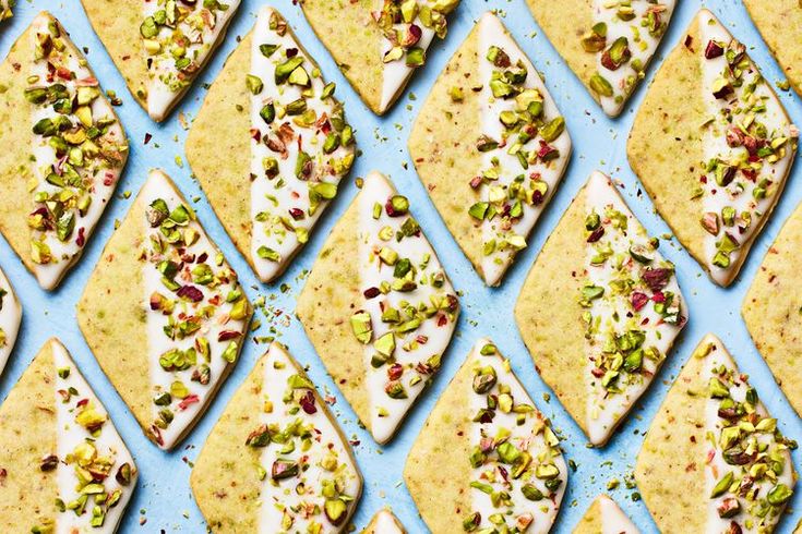 several pieces of flatbread with pistachios and nuts on a blue surface