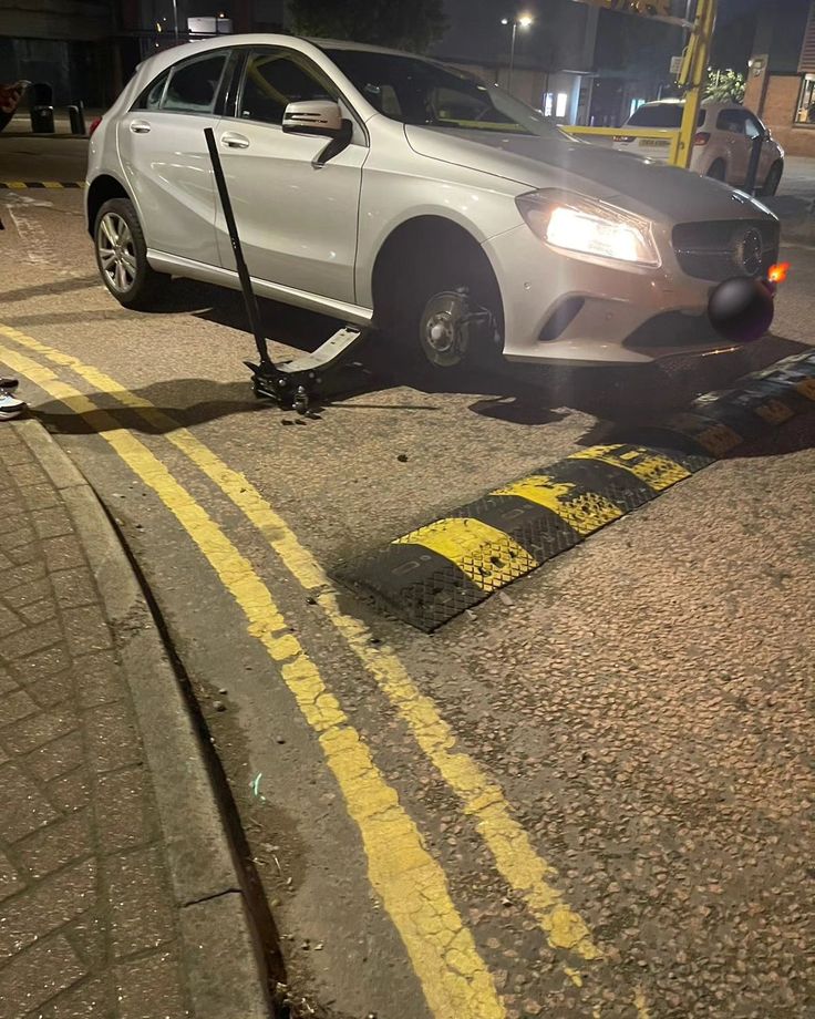 a white car is parked on the side of the road with a tow truck attached to it