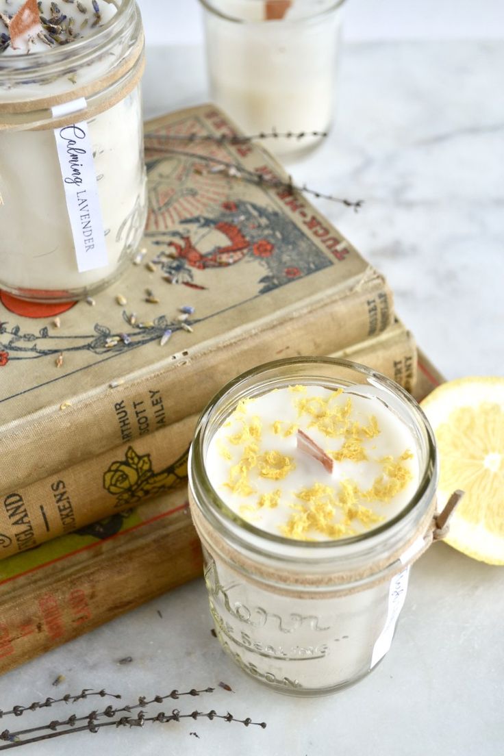 a glass jar filled with yellow flowers sitting on top of a table next to an open book