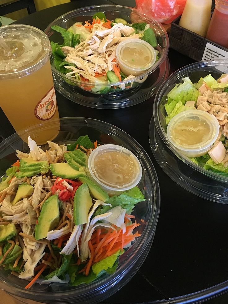 three plastic containers filled with different types of salads and drinks on top of a table