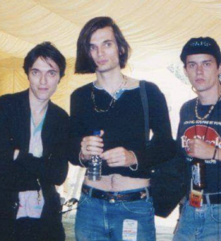 four young men standing next to each other in front of a white tent with yellow drapes