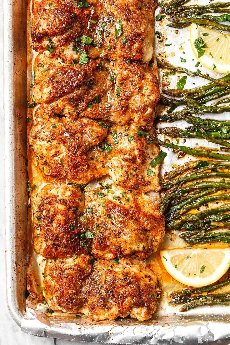 chicken and asparagus casserole in a baking pan with lemon wedges