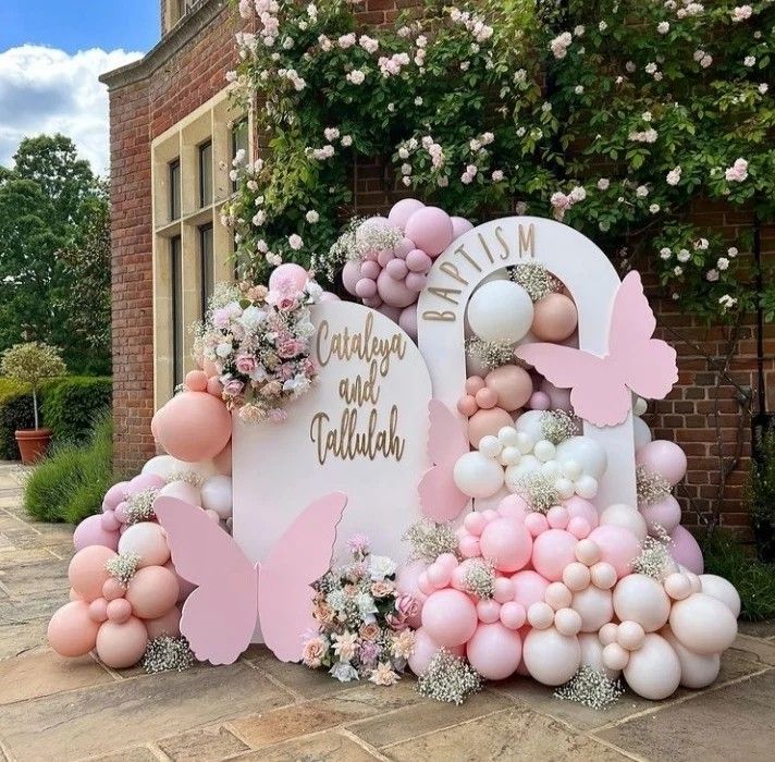 a pink and white balloon arch with balloons in the shape of flowers, butterflies and hearts