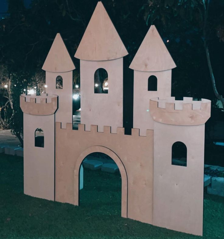 a castle made out of cardboard sitting in the middle of a park at night time