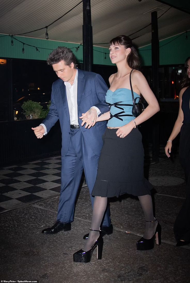 a man in a suit and tie walking next to a woman wearing high heeled shoes