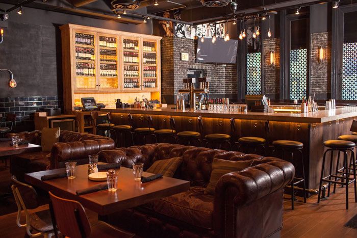 a bar with brown leather couches and wooden tables