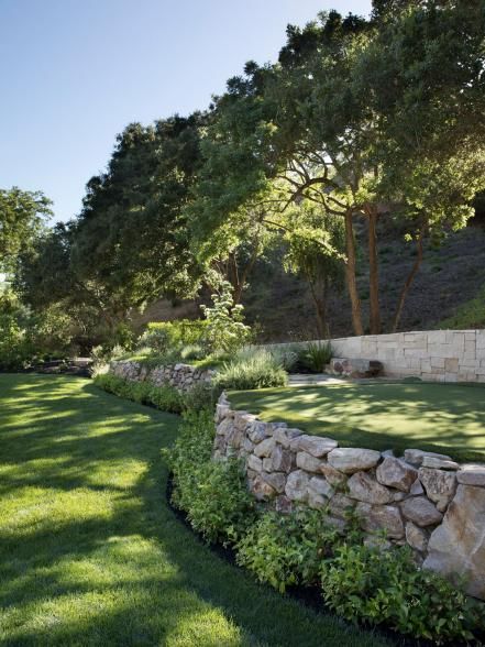 a stone wall in the middle of a grassy field