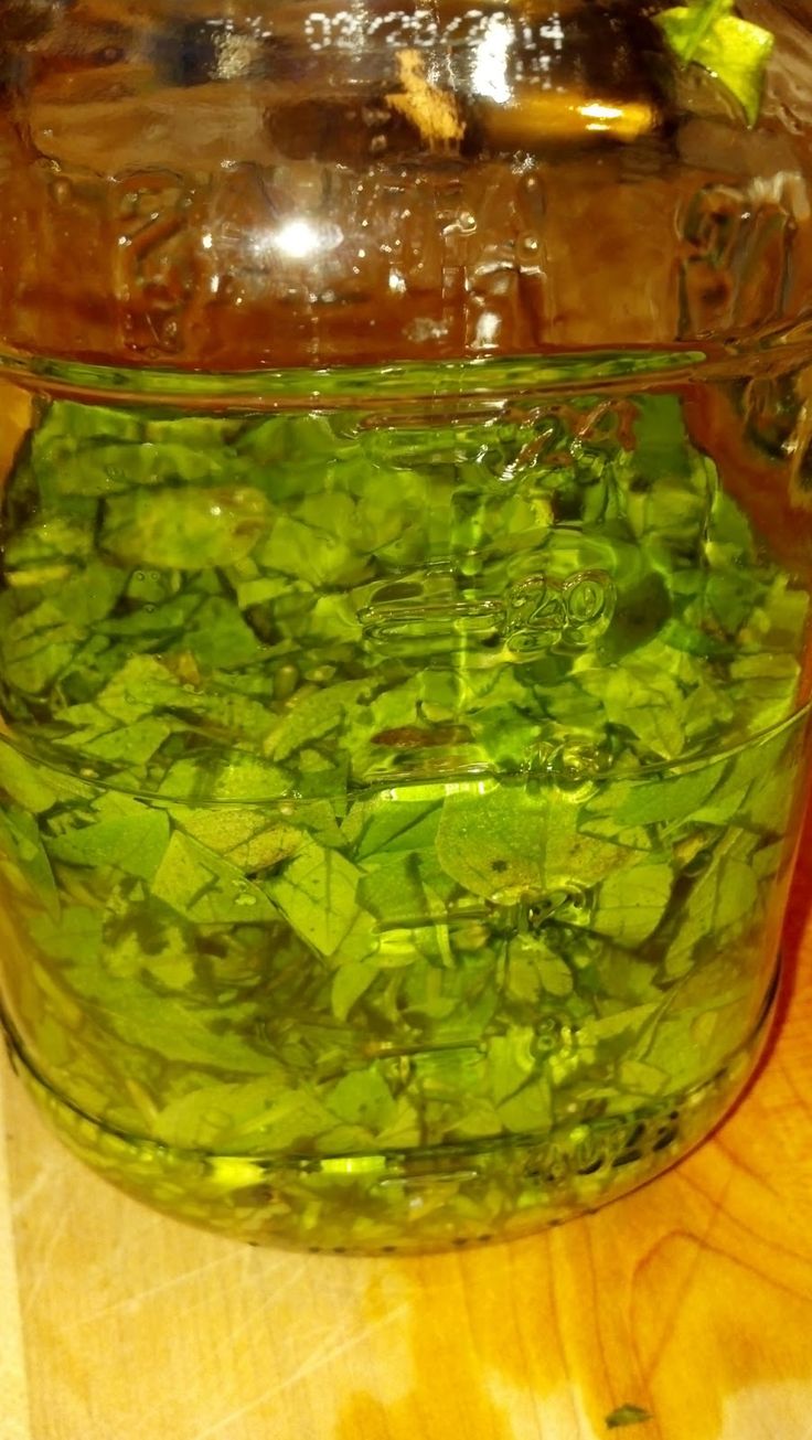 a jar filled with green vegetables sitting on top of a wooden table