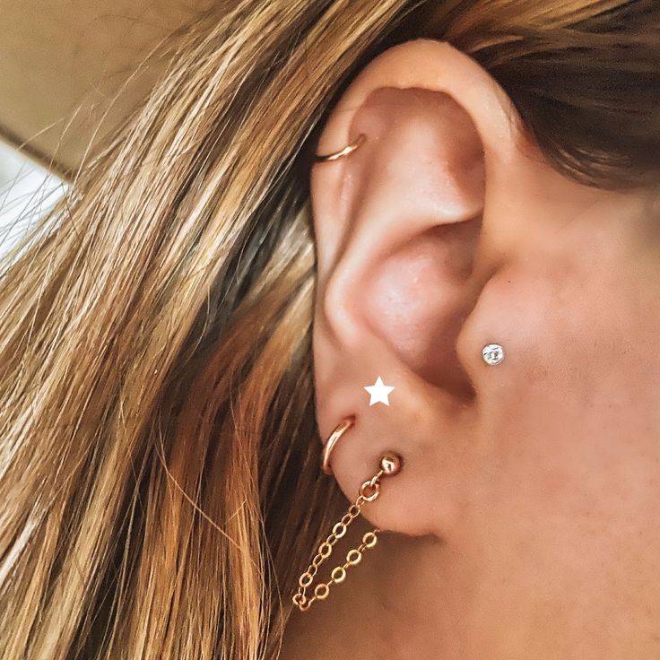 a close up of a person wearing gold ear piercings with stars on the side