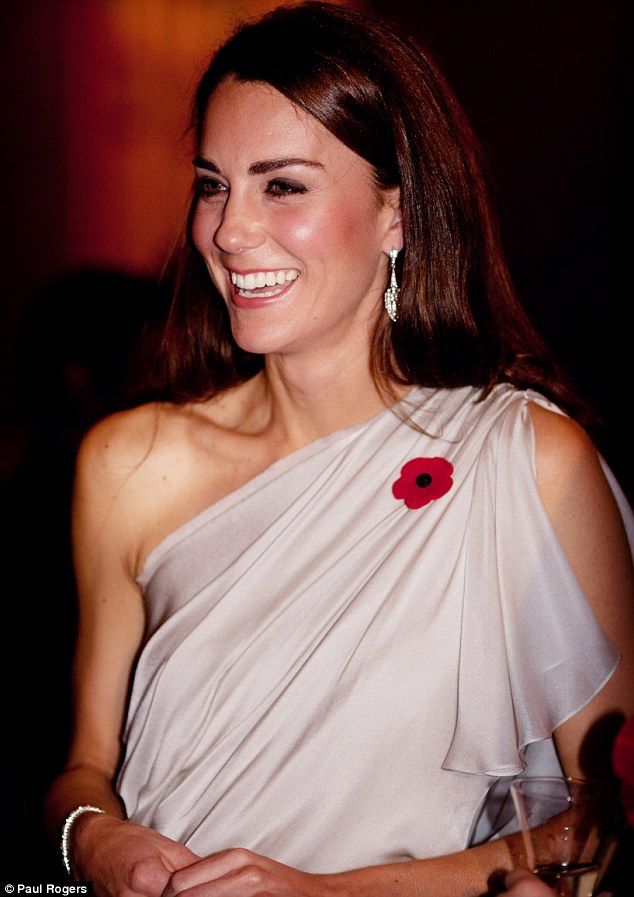 a woman in a white dress smiling and wearing a red flower on her left shoulder