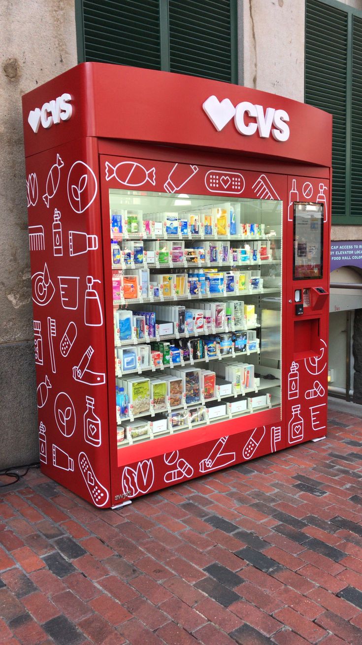 a red vending machine sitting on the side of a street