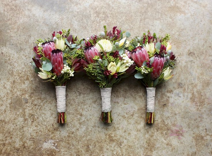 three bouquets of flowers sitting on top of a stone wall next to each other