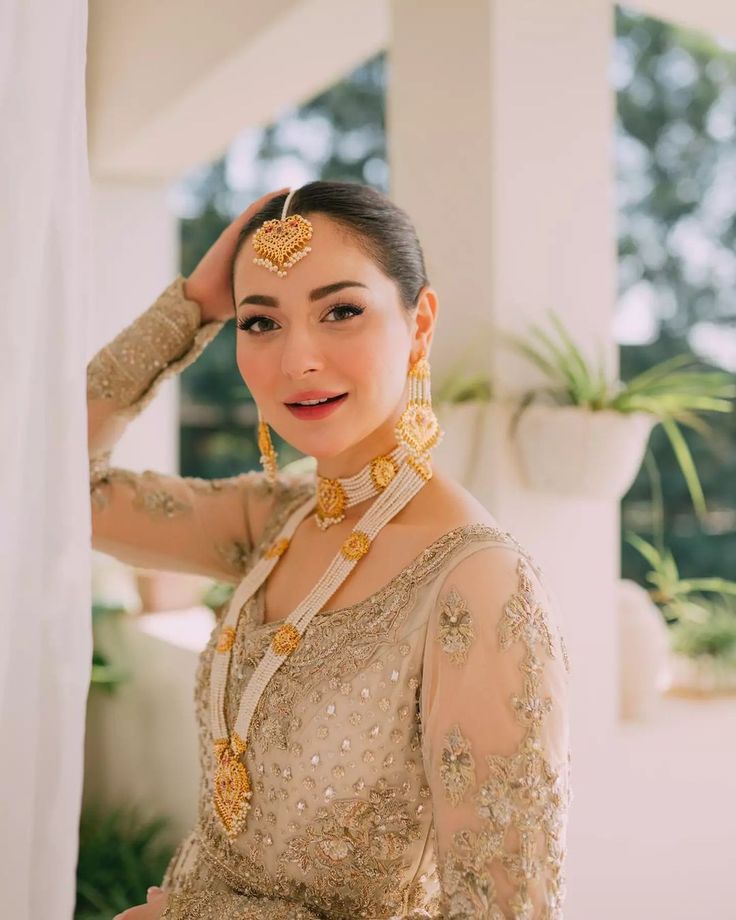 a woman in a bridal outfit posing for the camera with her hand on her head