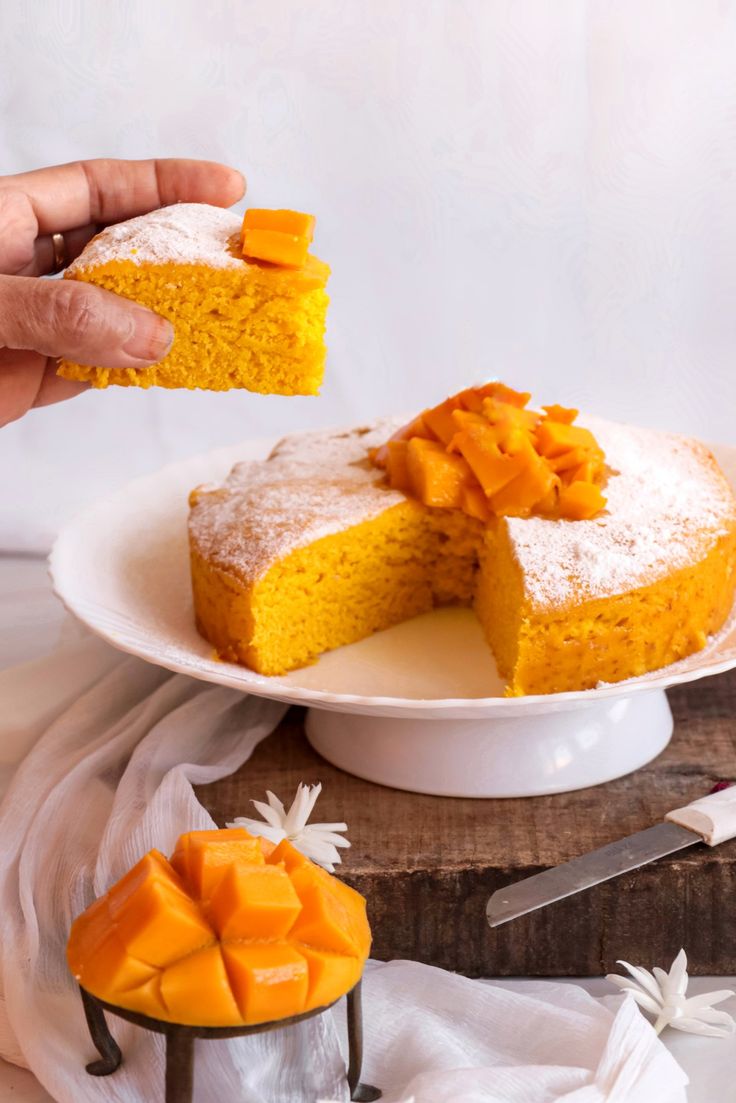 a person holding a piece of cake over a white plate with slices cut out of it