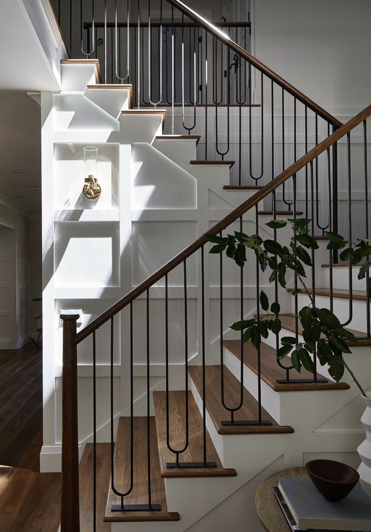 there is a plant that is growing on the stair railing in this house with white walls and wood flooring