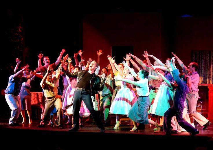 a group of people standing on top of a stage with their arms in the air