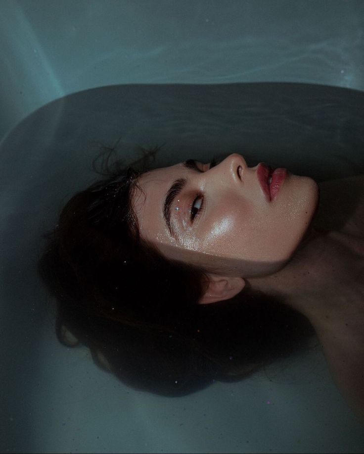 a woman laying in a bathtub with her eyes closed